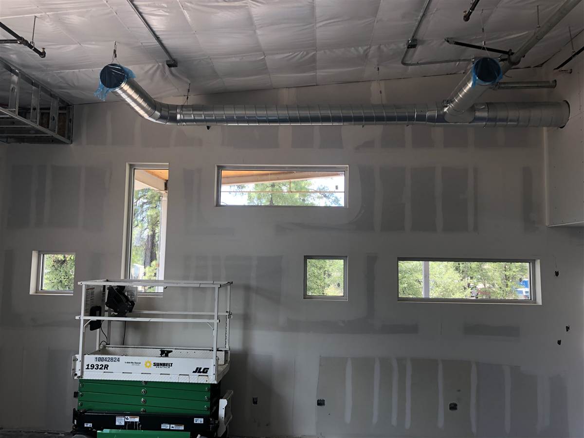 Taped drywall wall with windows and a scissor lift